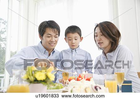 Stock Image - Family celebrating son's birthday at home. Fotosearch