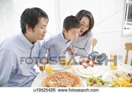 Family celebrating son's birthday at home View Large Photo Image Stock Photograph - Family celebrating son's birthday at home. Fotosearch