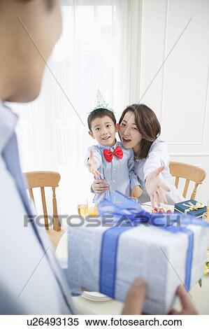 Stock Photography - Family celebrating son's birthday at home. Fotosearch