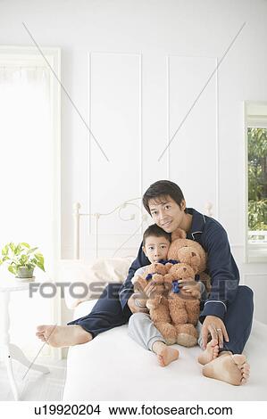 Picture - Father and son sitting in bed. Fotosearch
