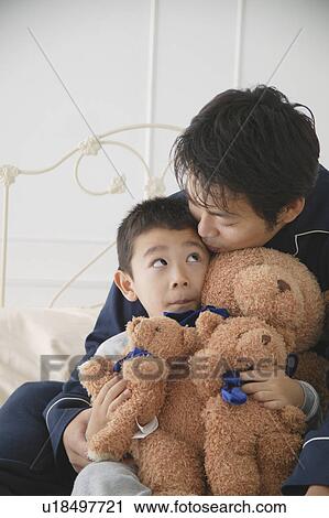 Stock Image - Father and son sitting in bed. Fotosearch