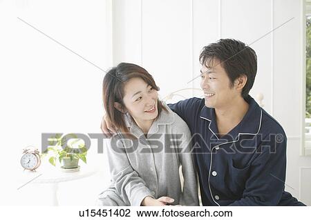 Stock Image - Mid adult couple sitting in bed. Fotosearch