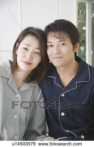 Stock Photo - Mid adult couple sitting in bed. Fotosearch