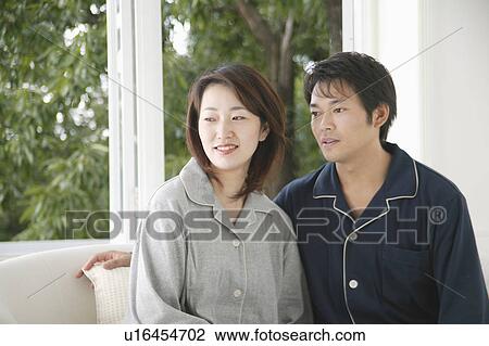 Stock Image - Mid adult couple sitting in sofa. Fotosearch
