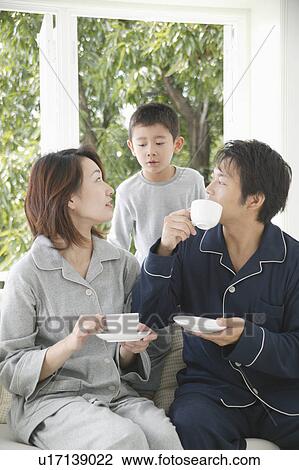 Stock Image - Mother and father holding cup with son standing behind. Fotosearch