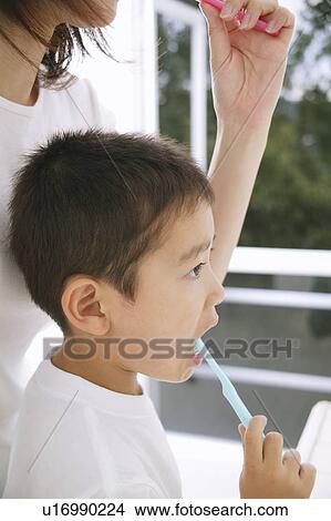 Picture - Mother and son brushing teeth, side view. Fotosearch