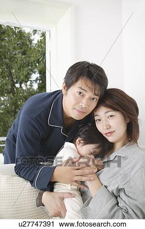Mother holding baby girl with father standing behind View Large Photo Image Stock Image - Mother holding baby girl with father standing behind. Fotosearch