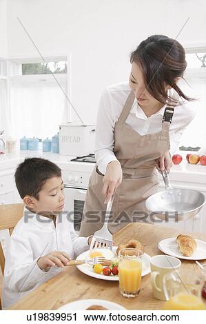 Stock Image - Mother serving son breakfast. Fotosearch