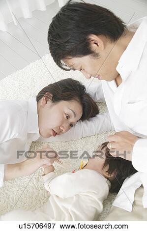 Stock Photo - Baby girl sleeping with parents watching. Fotosearch