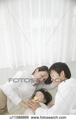 Stock Photograph - Baby girl sleeping with parents watching. Fotosearch