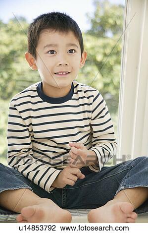 Stock Image - Boy sitting on windowsill. Fotosearch
