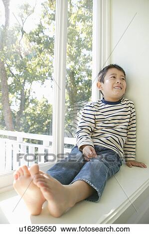 Stock Image - Boy sitting on windowsill. Fotosearch