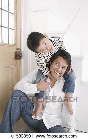 Stock Image - Father giving son piggyback. Fotosearch