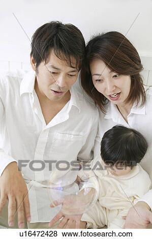 Stock Photo - Father, mother and baby girl watching bubbles.. Fotosearch