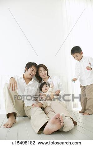 Stock Image - Son playing with bubbles and parents watching with smile.. Fotosearch