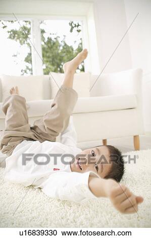 Boy lying down on floor View Large Photo Image Stock Image - Boy lying down on floor. Fotosearch