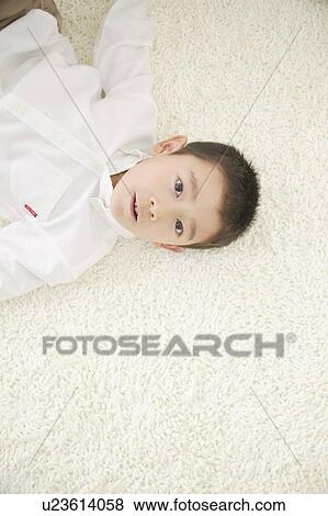 Boy lying down on floor View Large Photo Image Stock Photo - Boy lying down on floor. Fotosearch