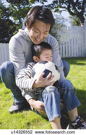 Stock Image - Father and son playing with ball. Fotosearch