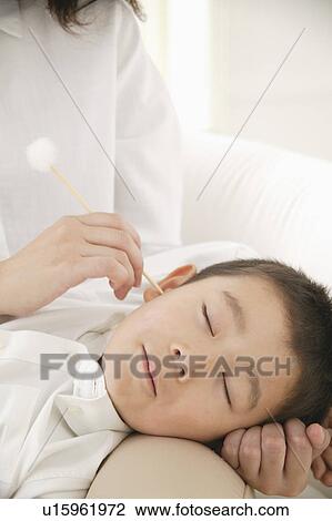 Stock Image - Mother cleaning son's ear, close-up. Fotosearch