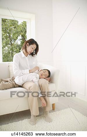 Stock Image - Mother cleaning son's ear. Fotosearch