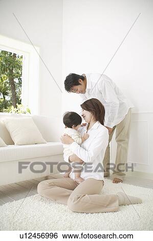 Mother holding baby girl with father standing View Large Photo Image Stock Photograph - Mother holding baby girl with father standing . Fotosearch