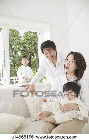 Son playing with bubbles and parents and baby girl watching View Large Photo Image Stock Photograph - Son playing with bubbles and parents and baby girl watching. Fotosearch