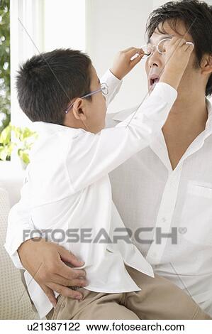 Stock Image - Son trying to take off father's glasses. Fotosearch