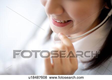 Stock Photo - Close-up of a young woman wearing headset. Fotosearch