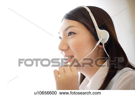 Stock Image - Close-up of young woman wearing headset. Fotosearch