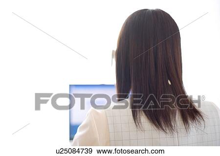 Stock Photo - Rear view of young woman working on computer. Fotosearch