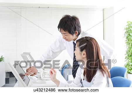Stock Photograph - Two young adults working on computer. Fotosearch