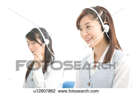 Stock Image - Two young women wearing headsets. Fotosearch