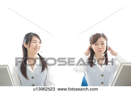Stock Image - Two young women wearing headsets. Fotosearch