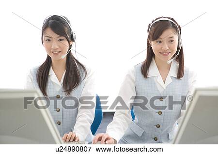 Stock Photo - Two young women with headsets working on computer. Fotosearch