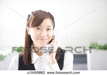 Stock Image - Young woman on phone looking at camera. Fotosearch