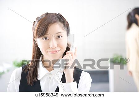 Young woman on phone looking at camera View Large Photo Image Stock Photo - Young woman on phone looking at camera. Fotosearch