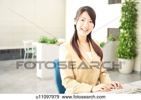 Young woman typing and looking at camera View Large Photo Image Stock Photo - Young woman typing and looking at camera. Fotosearch