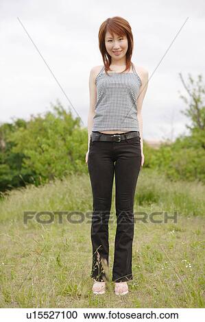 Portrait of young woman standing in field View Large Photo Image Stock Image - Portrait of young woman standing in field. Fotosearch