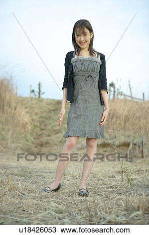 Stock Image - Portrait of young woman standing in field. Fotosearch