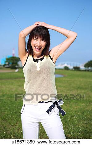 Portrait of young woman standing in field View Large Photo Image Stock Photo - Portrait of young woman standing in field. Fotosearch