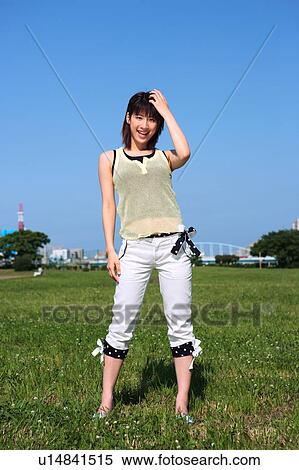 Stock Photography - Portrait of young woman standing in field. Fotosearch