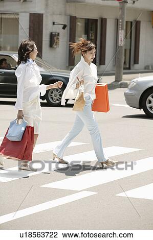 Stock Image - Two young women crossing road. Fotosearch