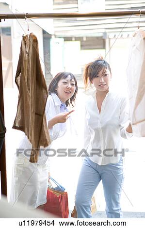 Two young women shopping at clothing store View Large Photo Image Picture - Two young women shopping at clothing store. Fotosearch