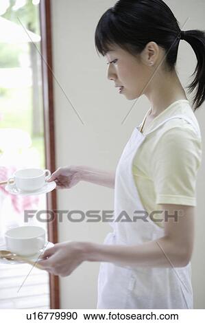 Young woman carrying cups and saucers View Large Photo Image Stock Image - Young woman carrying cups and saucers. Fotosearch