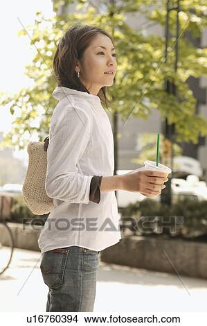 Picture - Young woman holding drink. Fotosearch