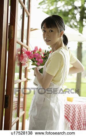 Young woman holding vase of flowers View Large Photo Image Stock Photo - Young woman holding vase of flowers. Fotosearch