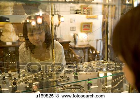 Stock Photo - Young woman looking in show case. Fotosearch