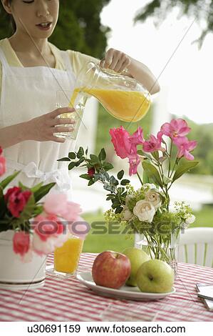 Young woman pouring orange juice into glass View Large Photo Image Stock Photo - Young woman pouring orange juice into glass. Fotosearch