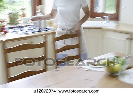 Picture - Young woman setting table, blurred motion. Fotosearch