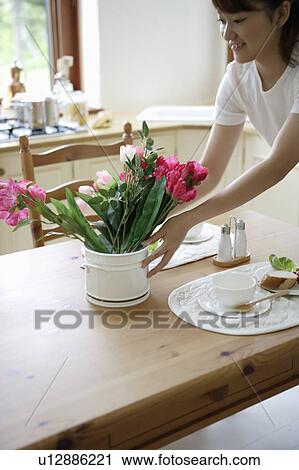 Stock Image - Young woman setting table. Fotosearch